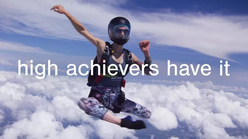 Skydiver in mid-air above the clouds, striking a dynamic pose with text overlaid that reads “high achievers have it.”
