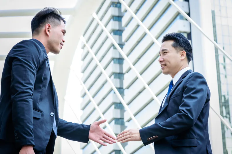 businessmen in suits about to shake hands as they close an M&A integration deal