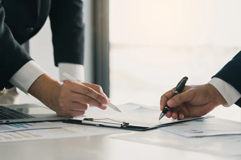 close-up shot of the hands of two businessmen signing a contract for a brand consultancy in Singapore