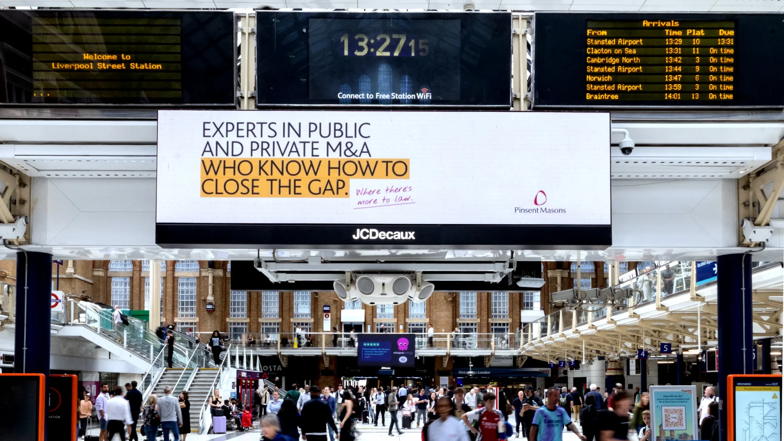 Liverpool Street: Pinsent Masons digital billboard above Liverpool Street station’s busy concourse, reading “Experts in public and private M&A who know how to close the gap.”