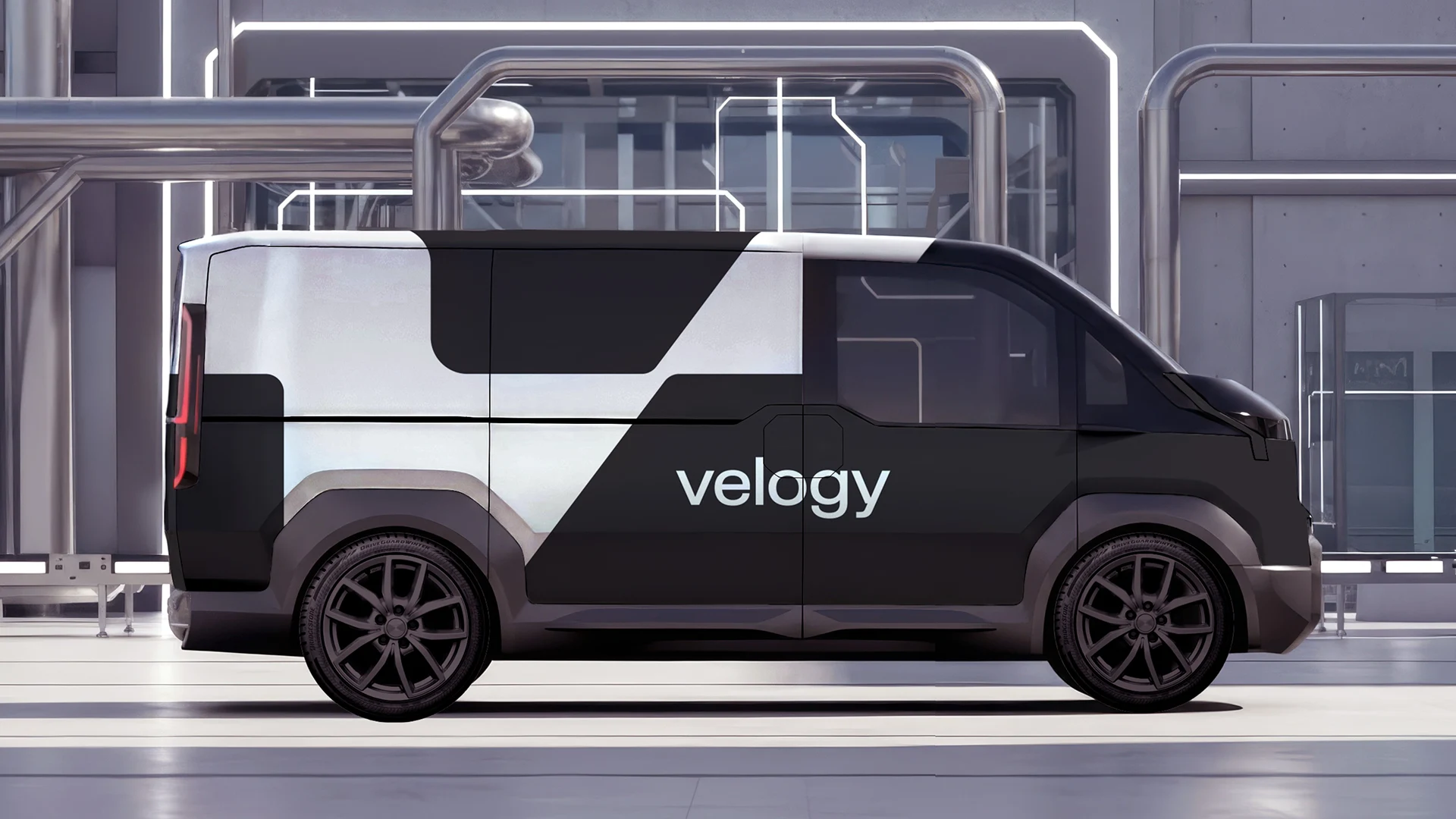 Black van with an oversized white Velogy symbol and wordmark, parked outside an industrial facility.