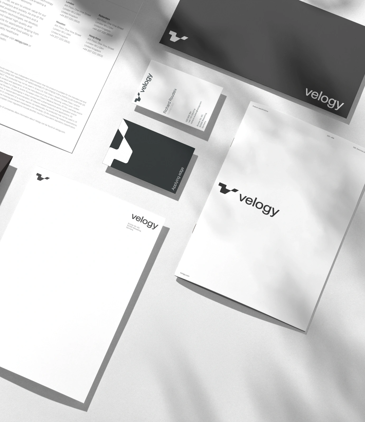 Black-and-white Velogy stationery suite featuring business cards, letterheads and an envelope with the logo and wordmark.